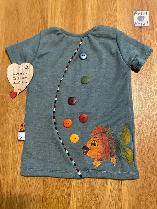 Ein T-Shirt aus Wolle/Seide Arctic Night mit einer Korkapplikation (Regenbogenfisch) und bunten Knöpfen als Blubberblasen, die aufsteigen.