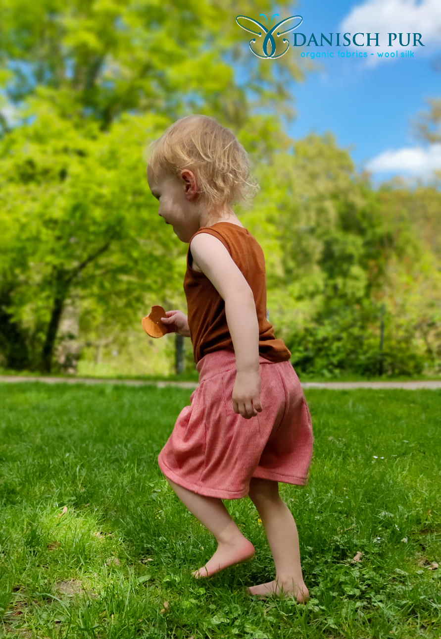 Kind in Wollkleidung rennend über Gras