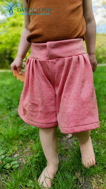 Kind mit Wolljersey Shorts auf einer Wiese