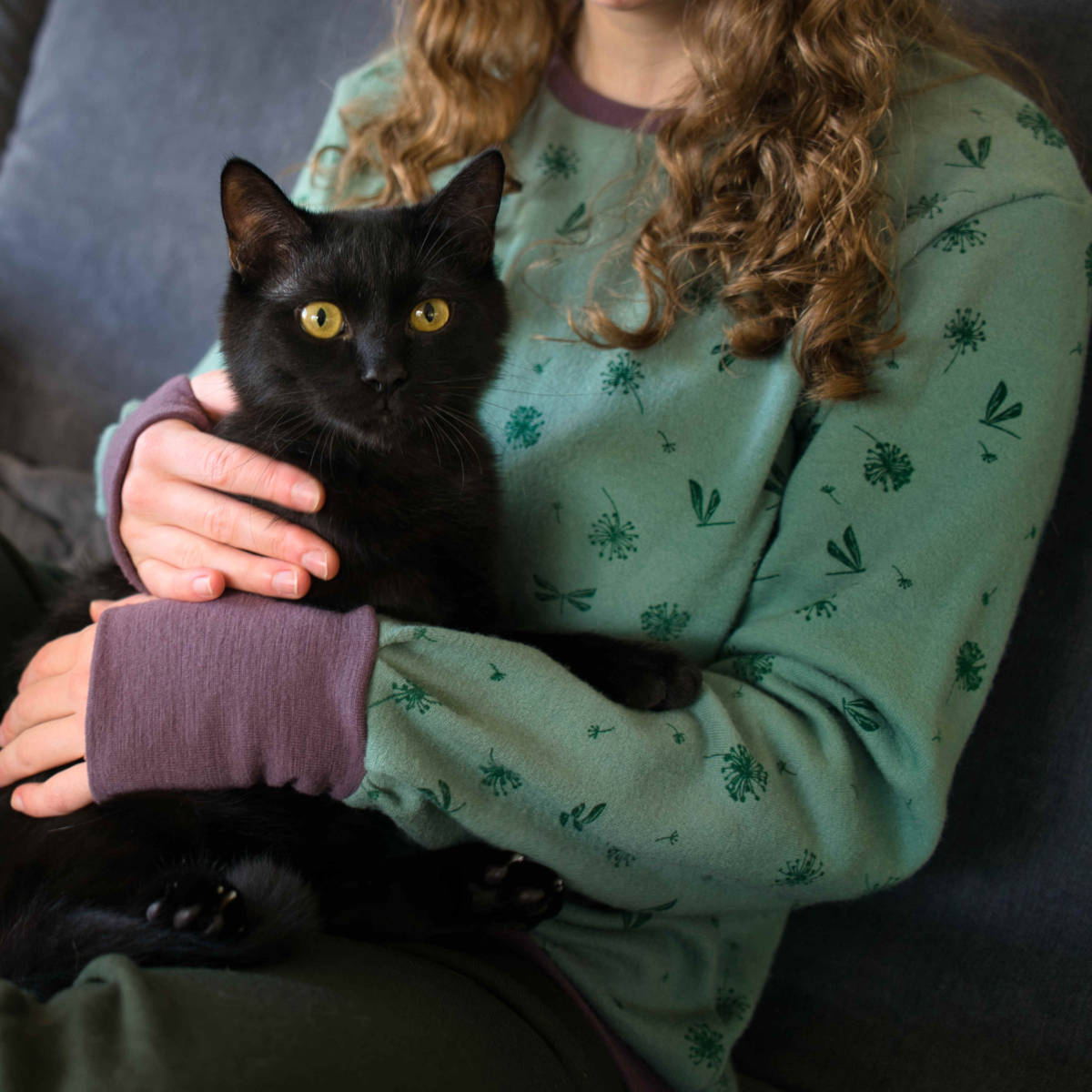 Frau in Wollpullover mit Katze im Arm.
